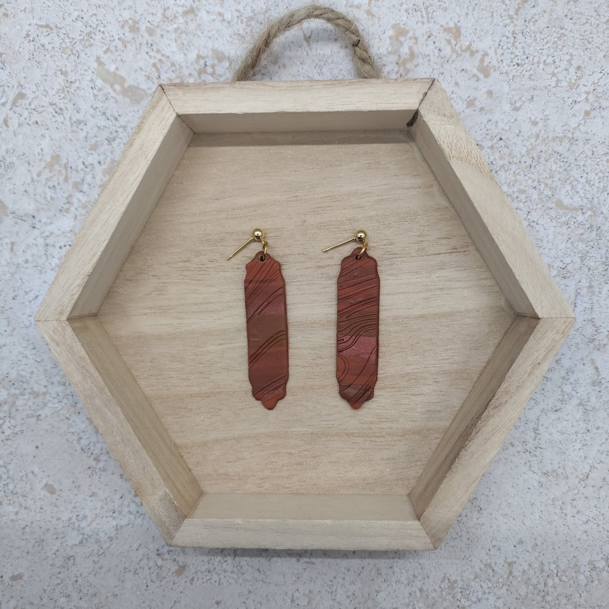 Wooden hexagonal tray with red stone earrings on a textured surface