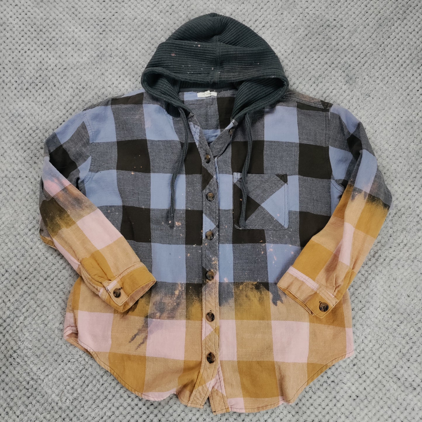 Plaid shirt with a hood on a textured gray surface