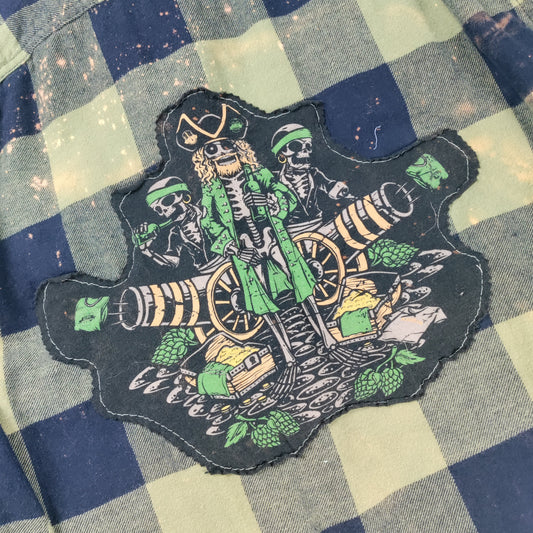 Checkered shirt with a pirate-themed patch featuring skeletons and barrels.