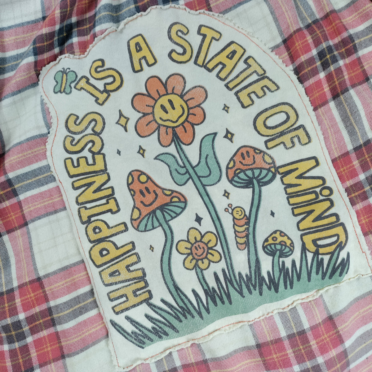 Floral patch with 'Happiness is a State of Mind' text on plaid fabric