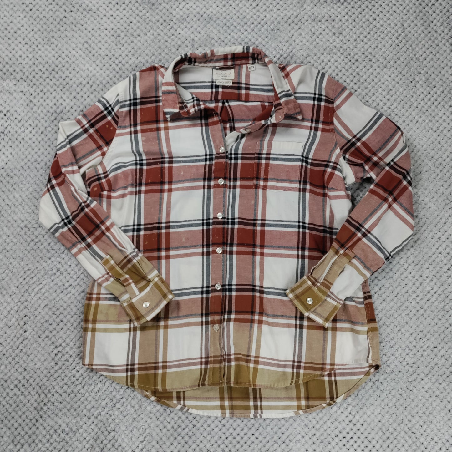 Plaid shirt with brown and beige accents on a textured gray background