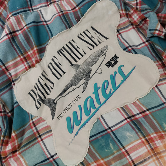 Sticker with a shark design and text on a plaid fabric background