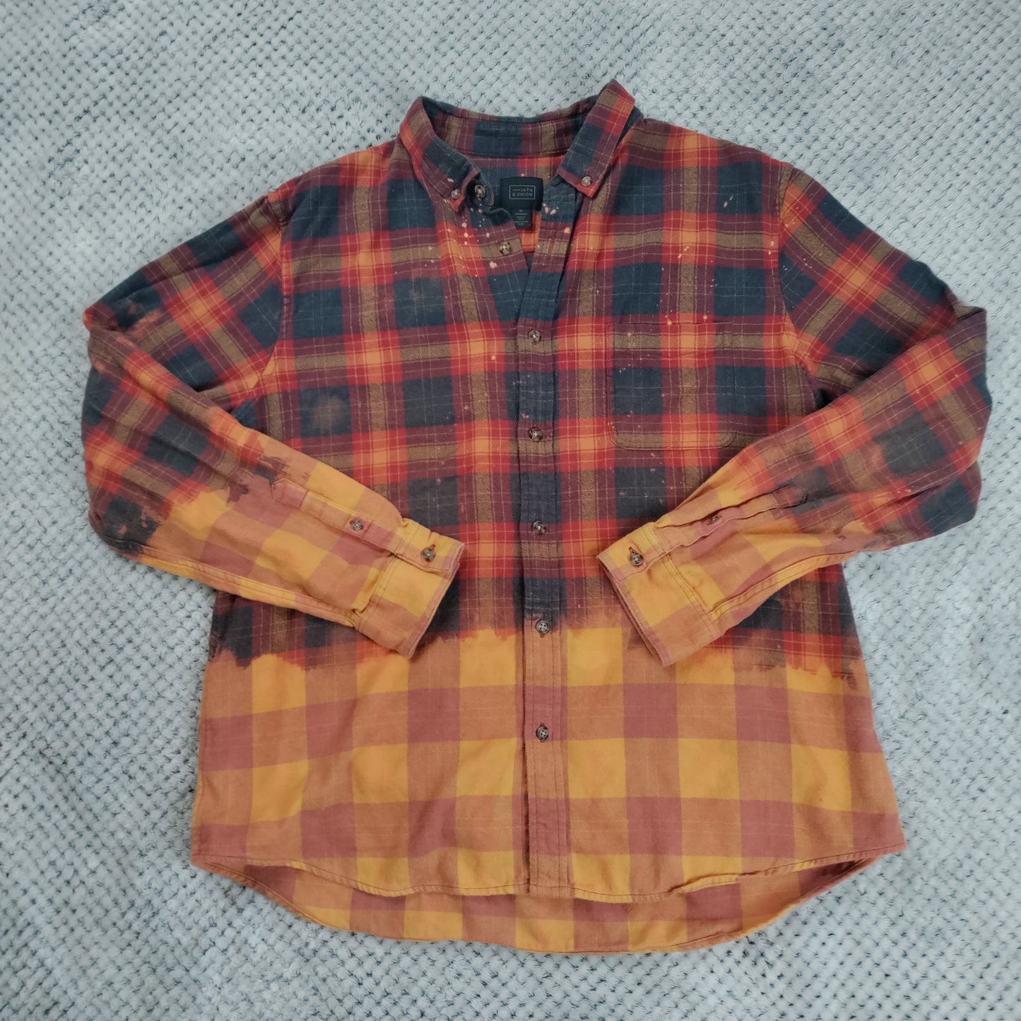 Plaid shirt with red and yellow pattern on a textured gray background