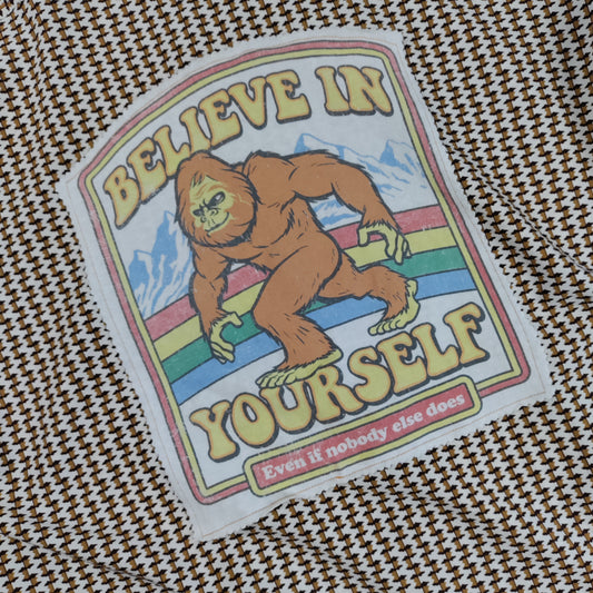 Sticker with a Sasquatch graphic and 'Believe in Yourself' text on a textured fabric background