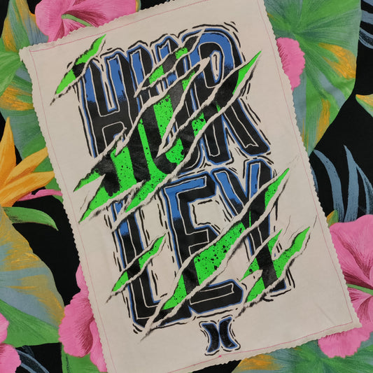 Textile patch with 'Higher Higher Higher' design on a colorful leafy background