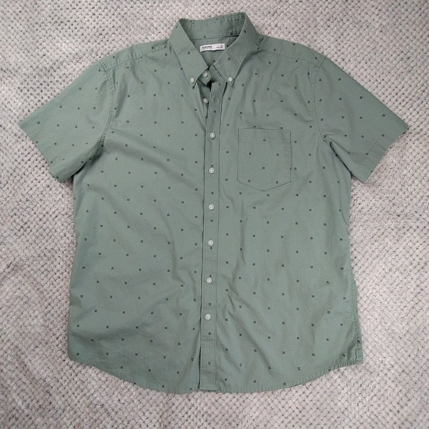 Green short-sleeve shirt with a subtle pattern on a textured gray background