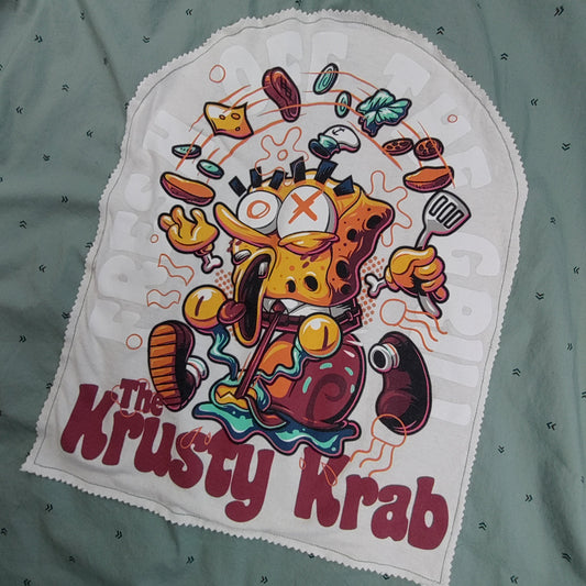 Embroidered patch of a cartoon character from 'The Krusty Krab' on a green fabric background.