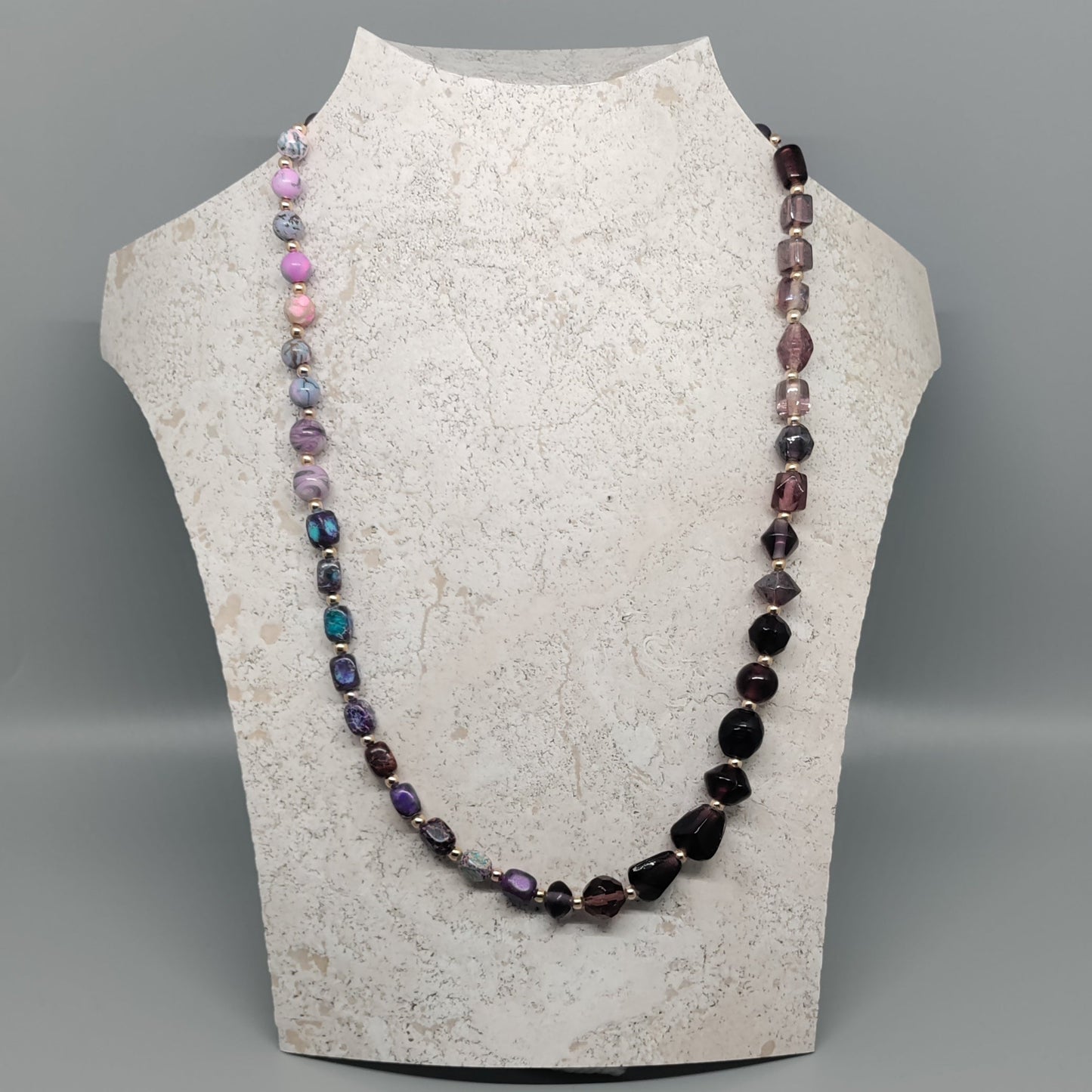 Necklace on a mannequin bust against a gray background