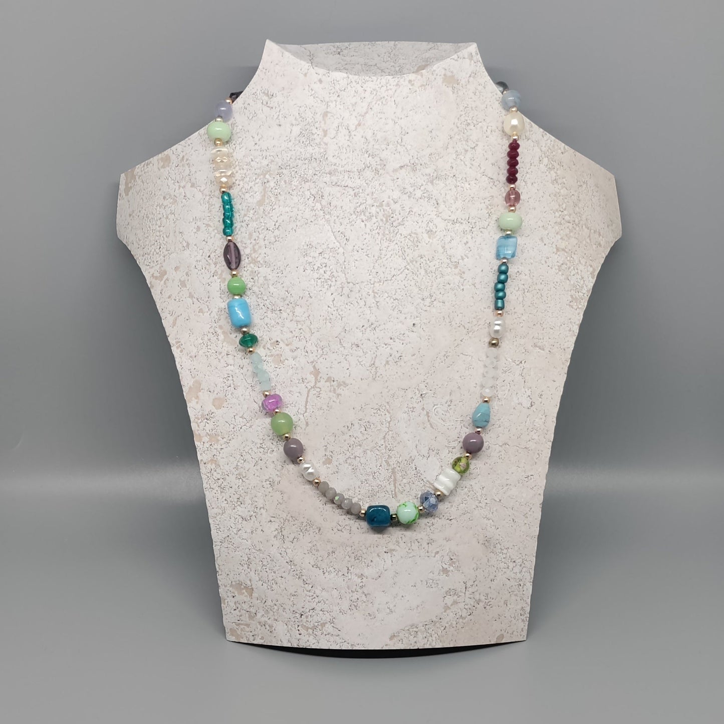 Necklace on a mannequin bust against a gray background