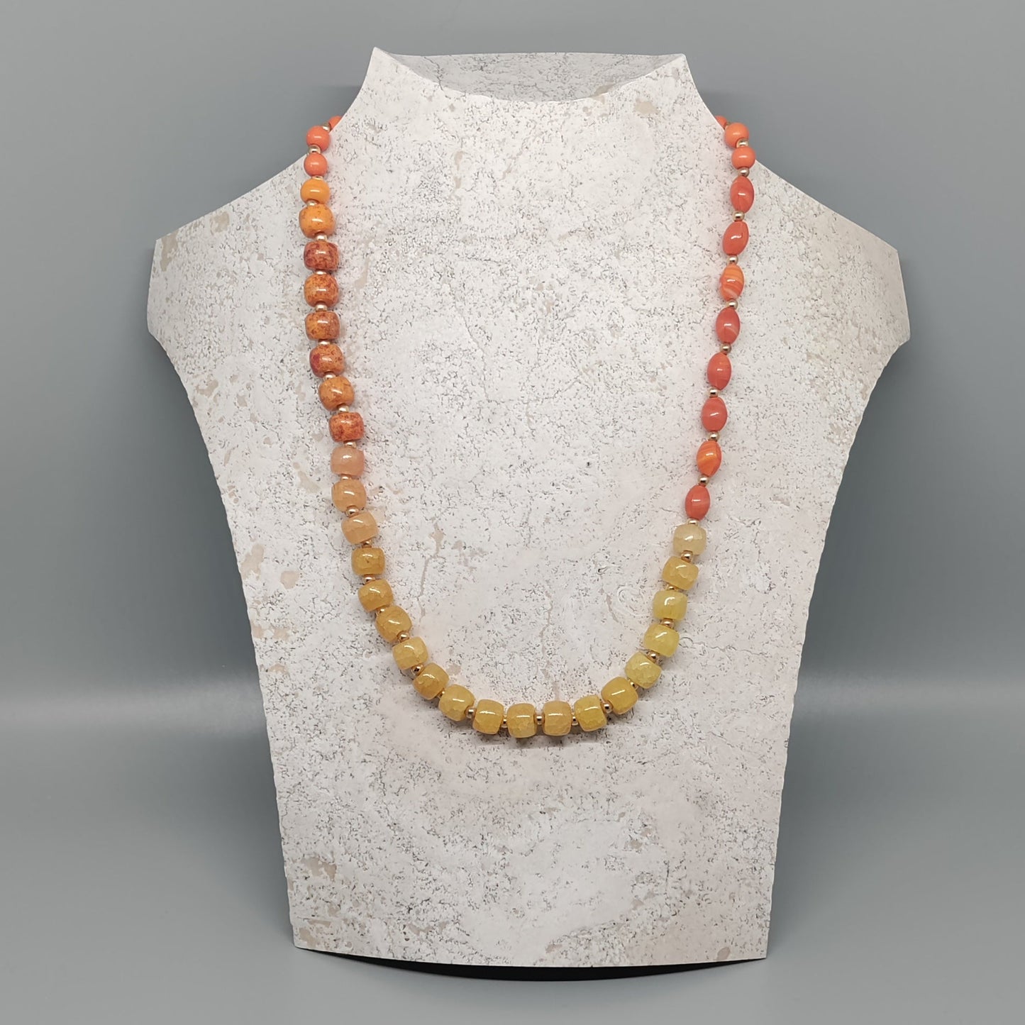 Necklace displayed on a mannequin bust against a gray background