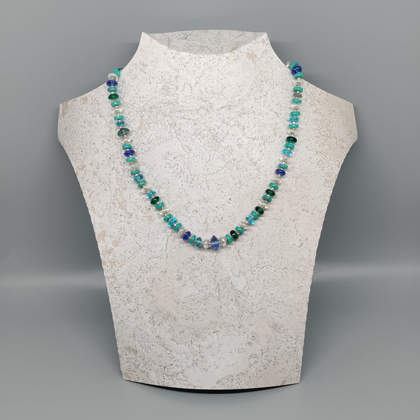 Necklace on a mannequin bust against a gray background