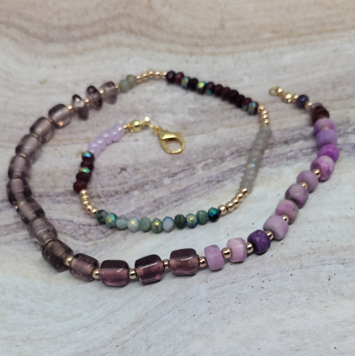 Beaded necklace and bracelet set on a light stone surface