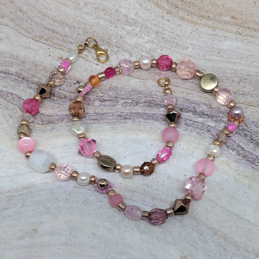 Beaded bracelet with pink and gold beads on a marble surface