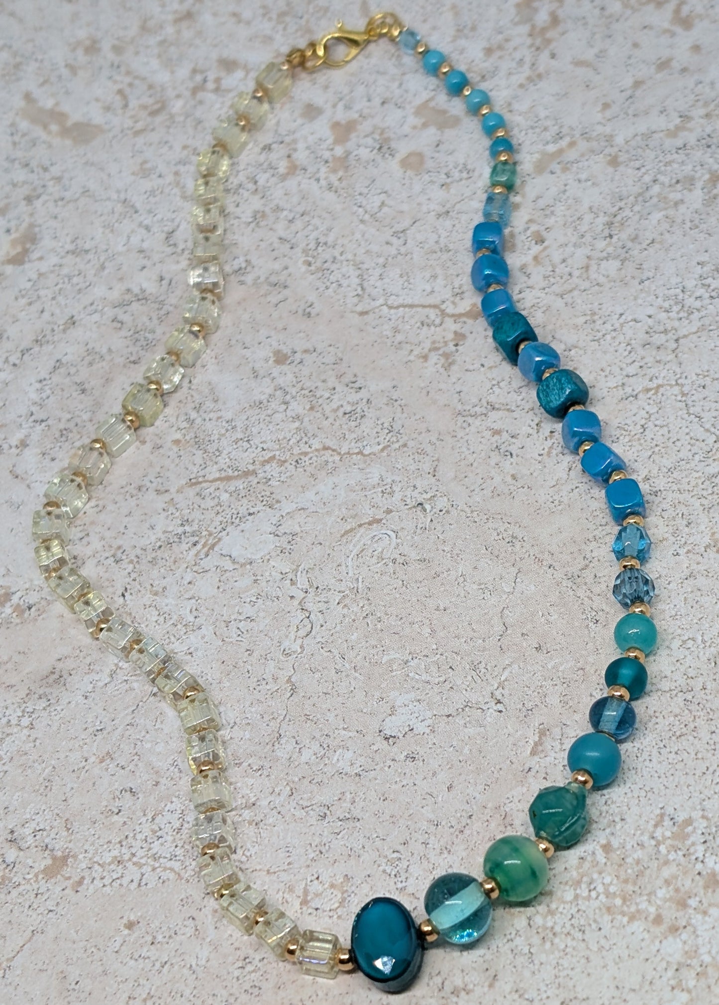 Necklace with blue and clear beads on a textured surface