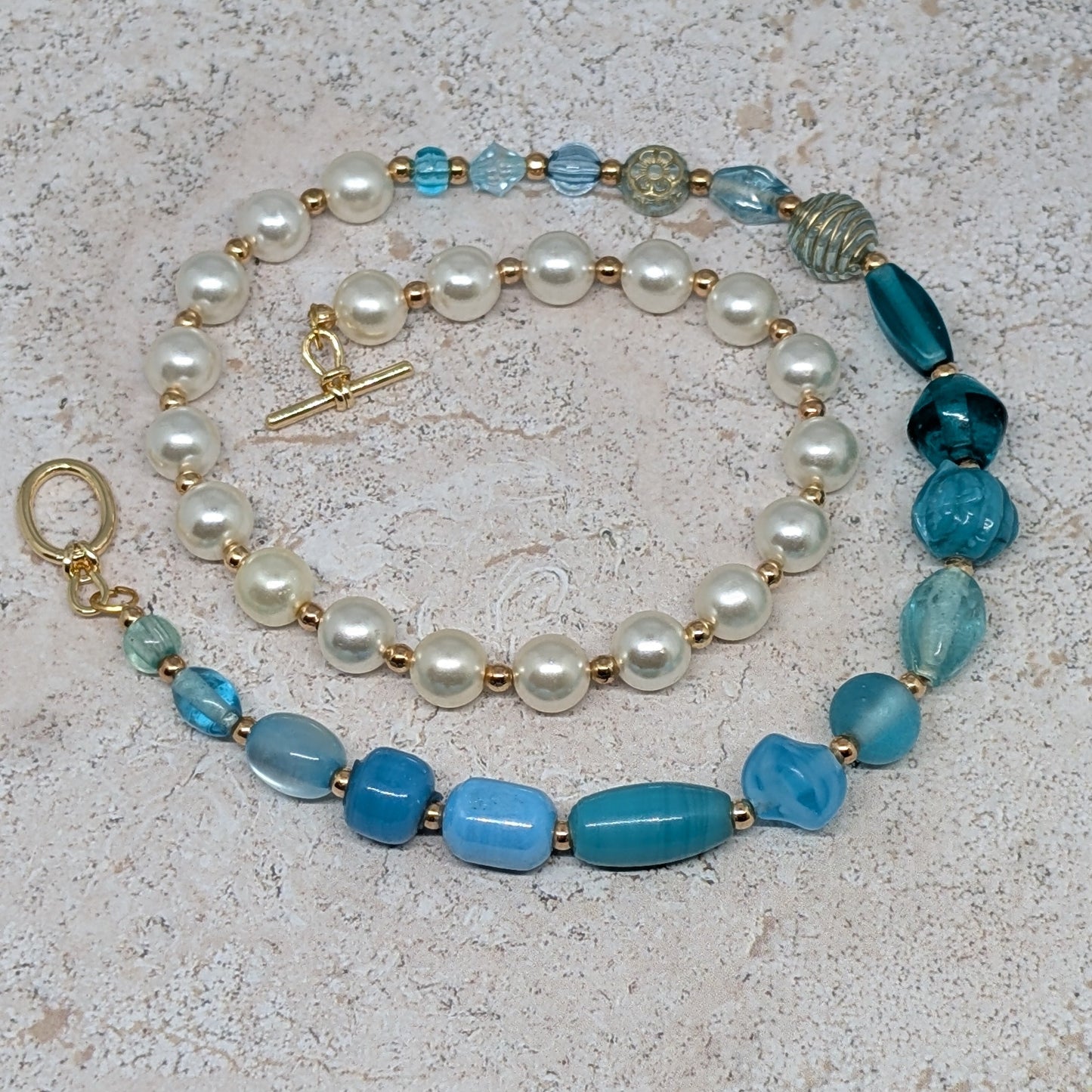 Necklace with pearls and blue beads on a textured surface