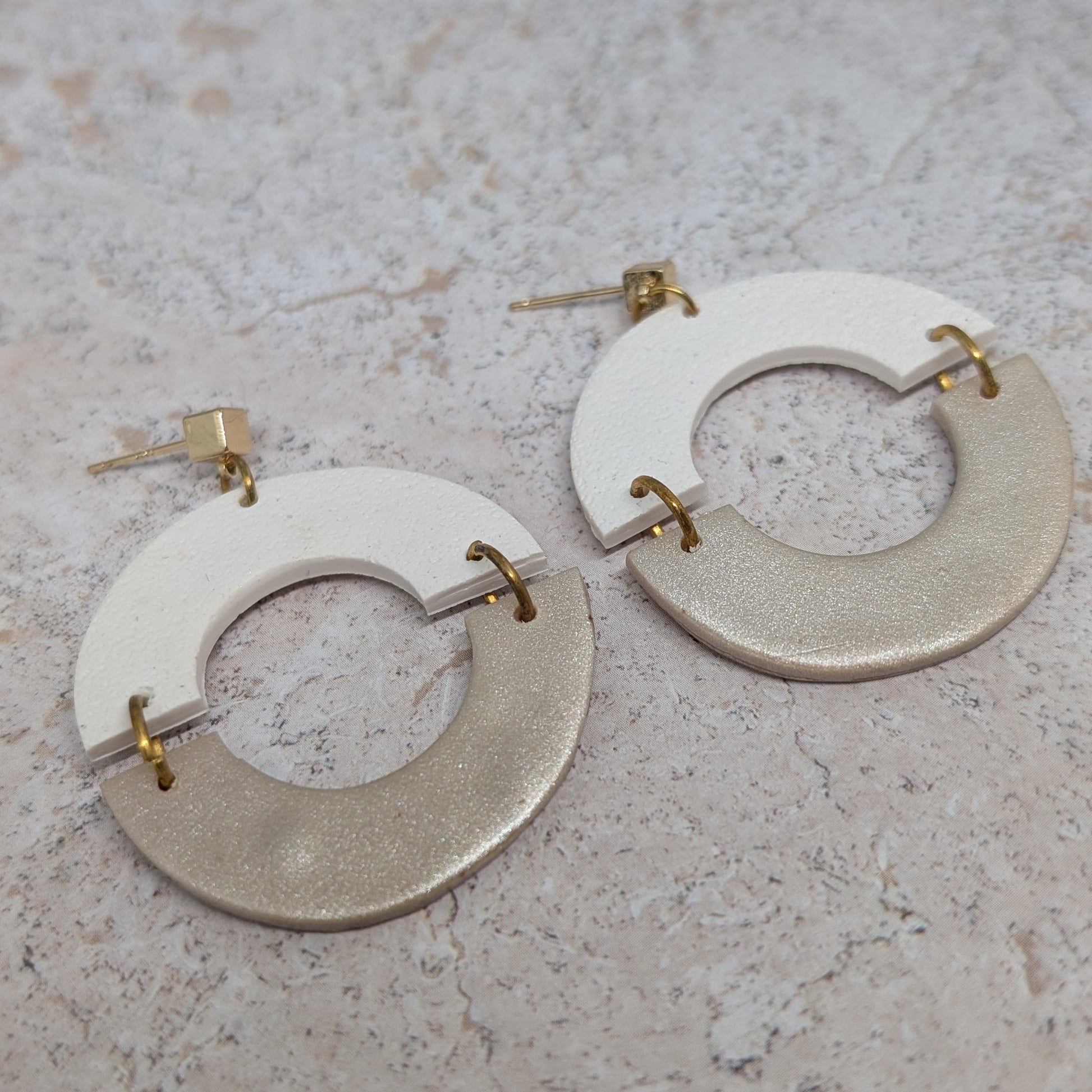 Pair of earrings with circular designs on a textured surface
