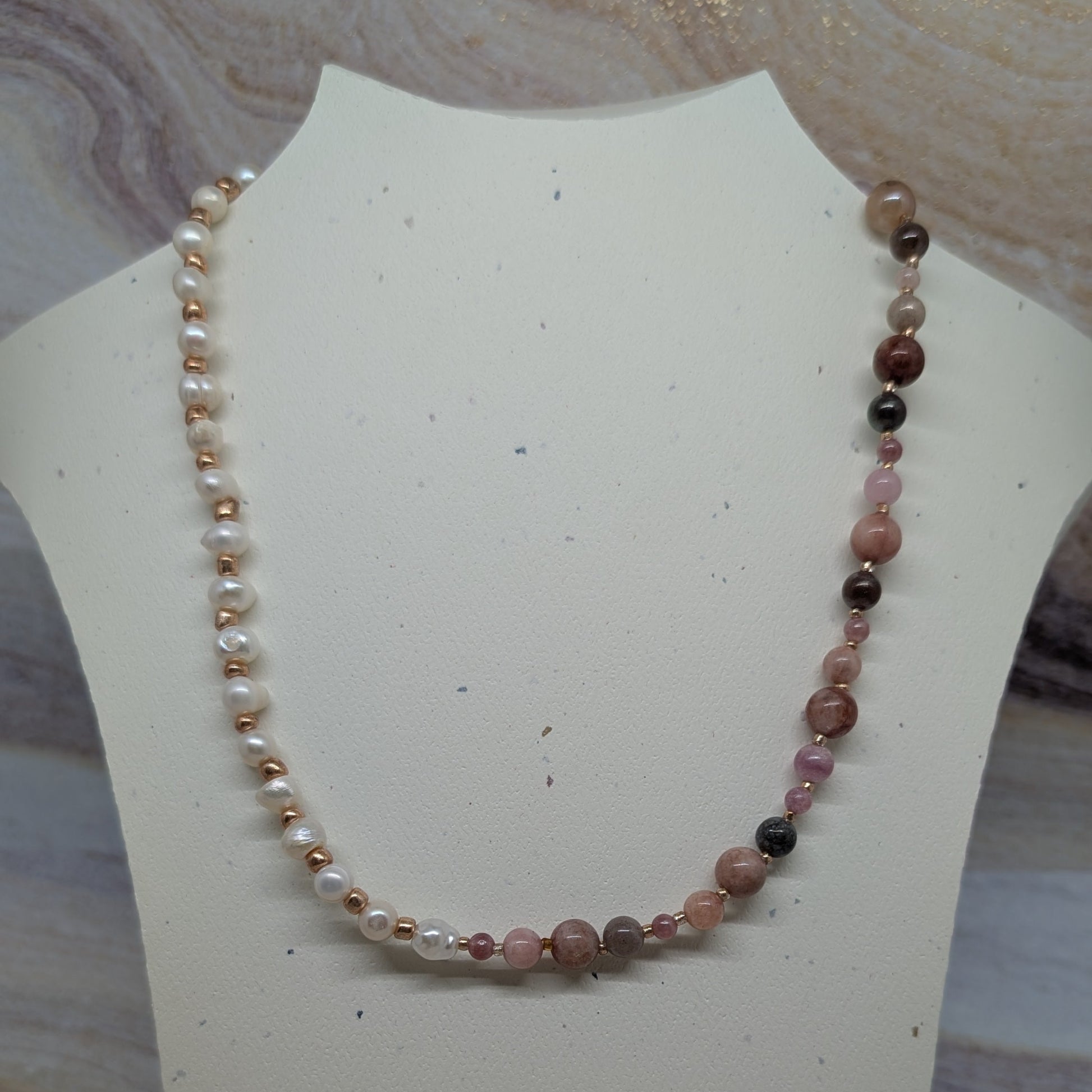 Necklace with multicolored beads on a white mannequin bust against a marble background
