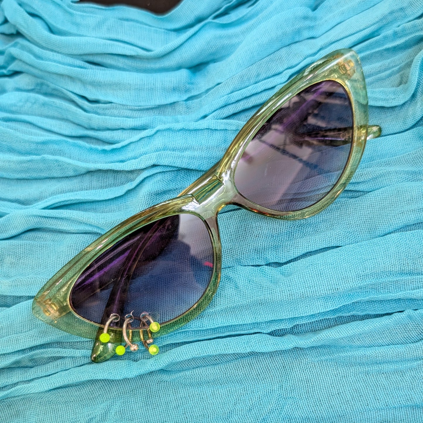 Gold-framed sunglasses with reflective lenses on a blue fabric background