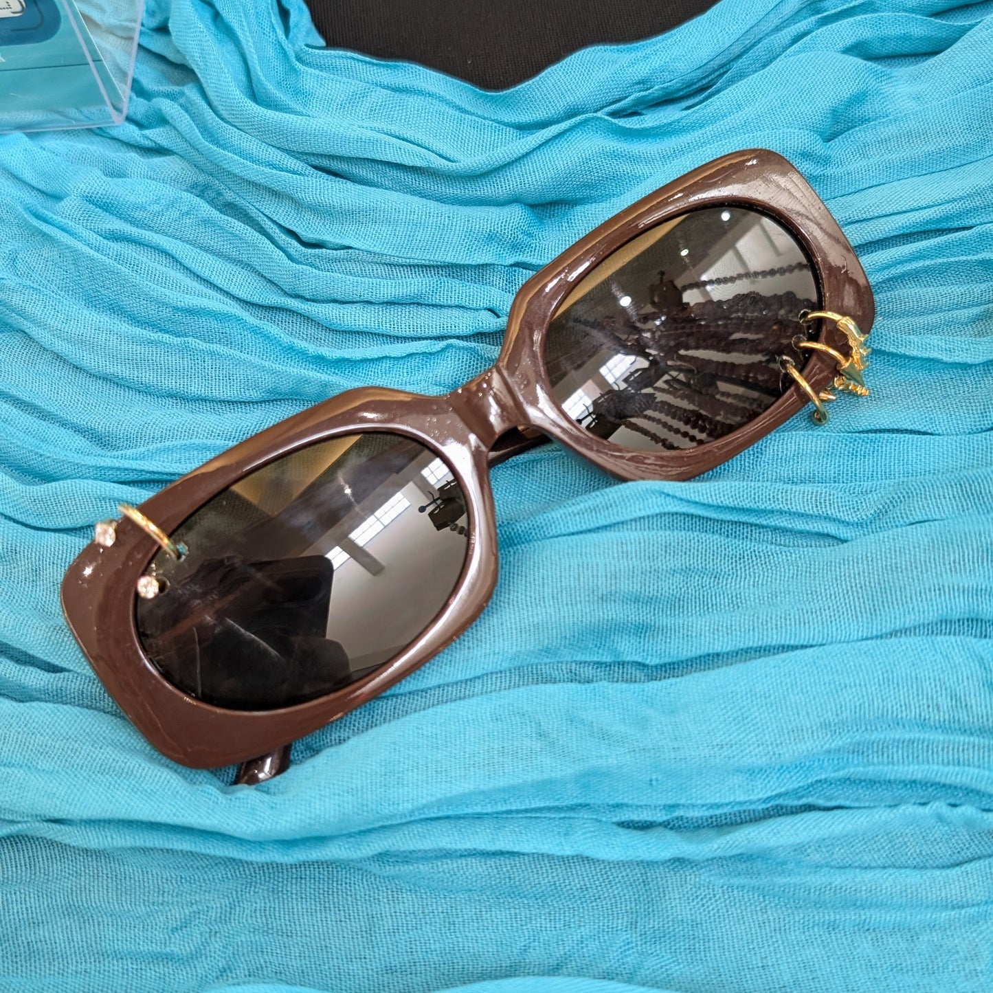 Sunglasses with brown frame and reflective lenses on a blue fabric background