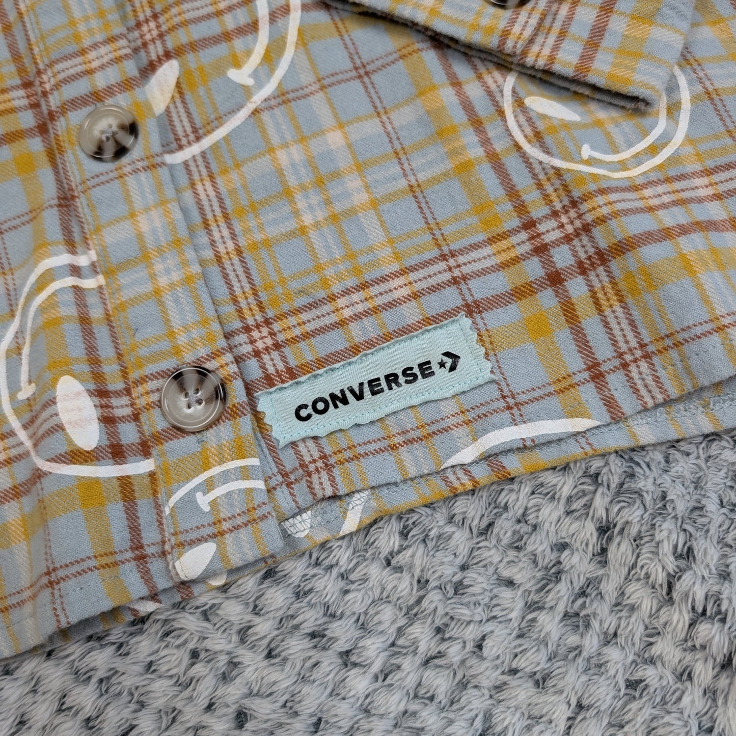 Close-up of a plaid shirt with a Converse label on a textured surface