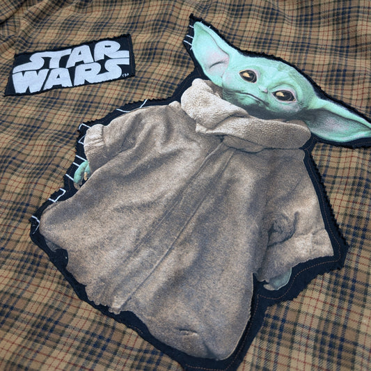 Plaid shirt with 'Star Wars' logo and Baby Yoda design on a checkered fabric background