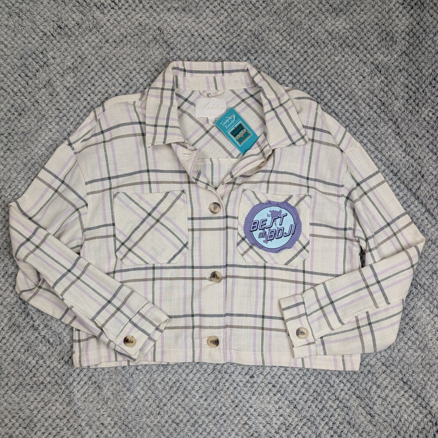Plaid jacket with a brand logo on a textured gray surface