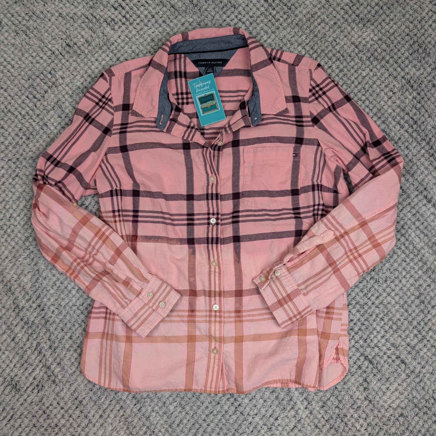 Pink plaid shirt with a tag on a textured gray surface