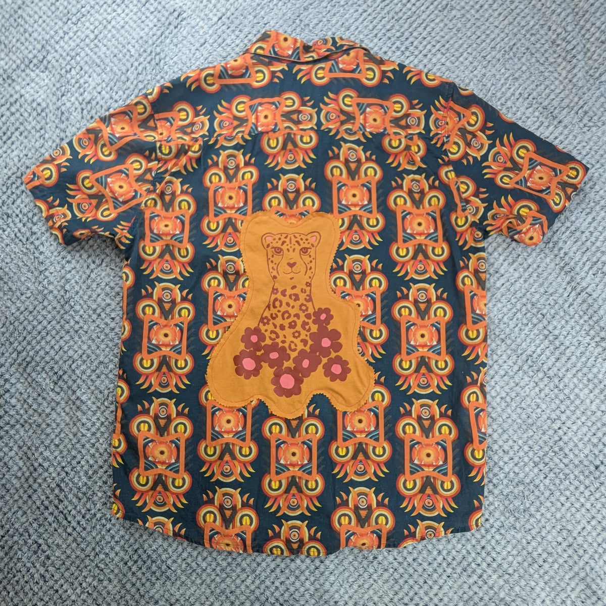 Short Sleeve button up shirt with bright orange graphic patterns. Featuring an orange and red cheetah graphic on a grey background.
