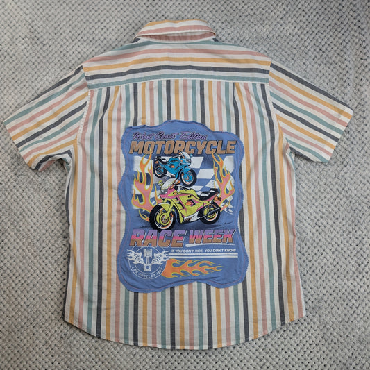 A short-sleeve button-up shirt with vertical stripes in beige, orange, green, and gray, featuring a large blue graphic print on the back with illustrations of motorcycles, flames, and the text 'MOTORCYCLE RACE WEEK'.