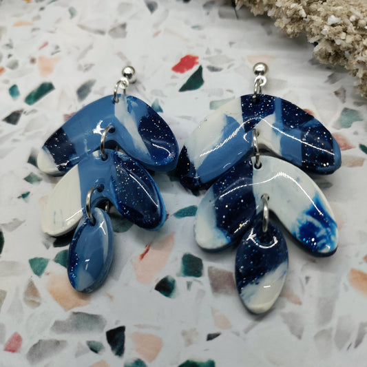 Pair of blue and white earrings on a terrazzo surface