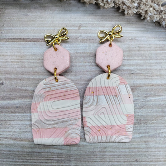 Pair of earrings with pink and white marbled design on a textured surface
