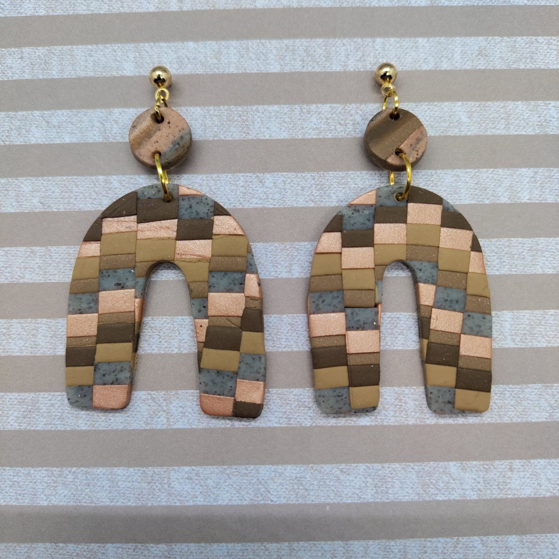 Pair of checkered earrings on a striped background