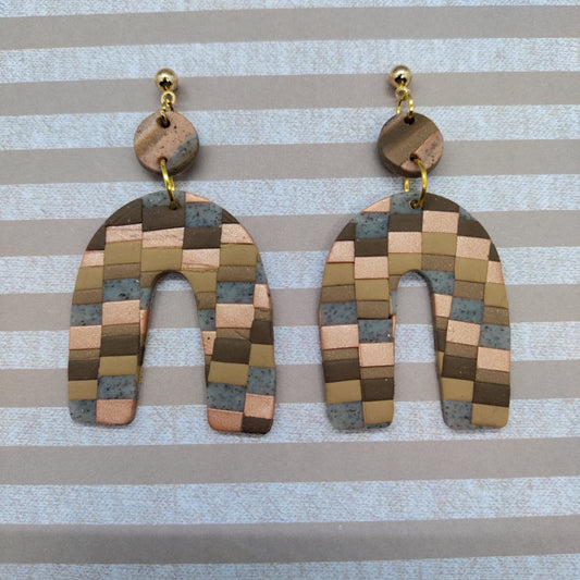 Pair of checkered earrings on a striped background