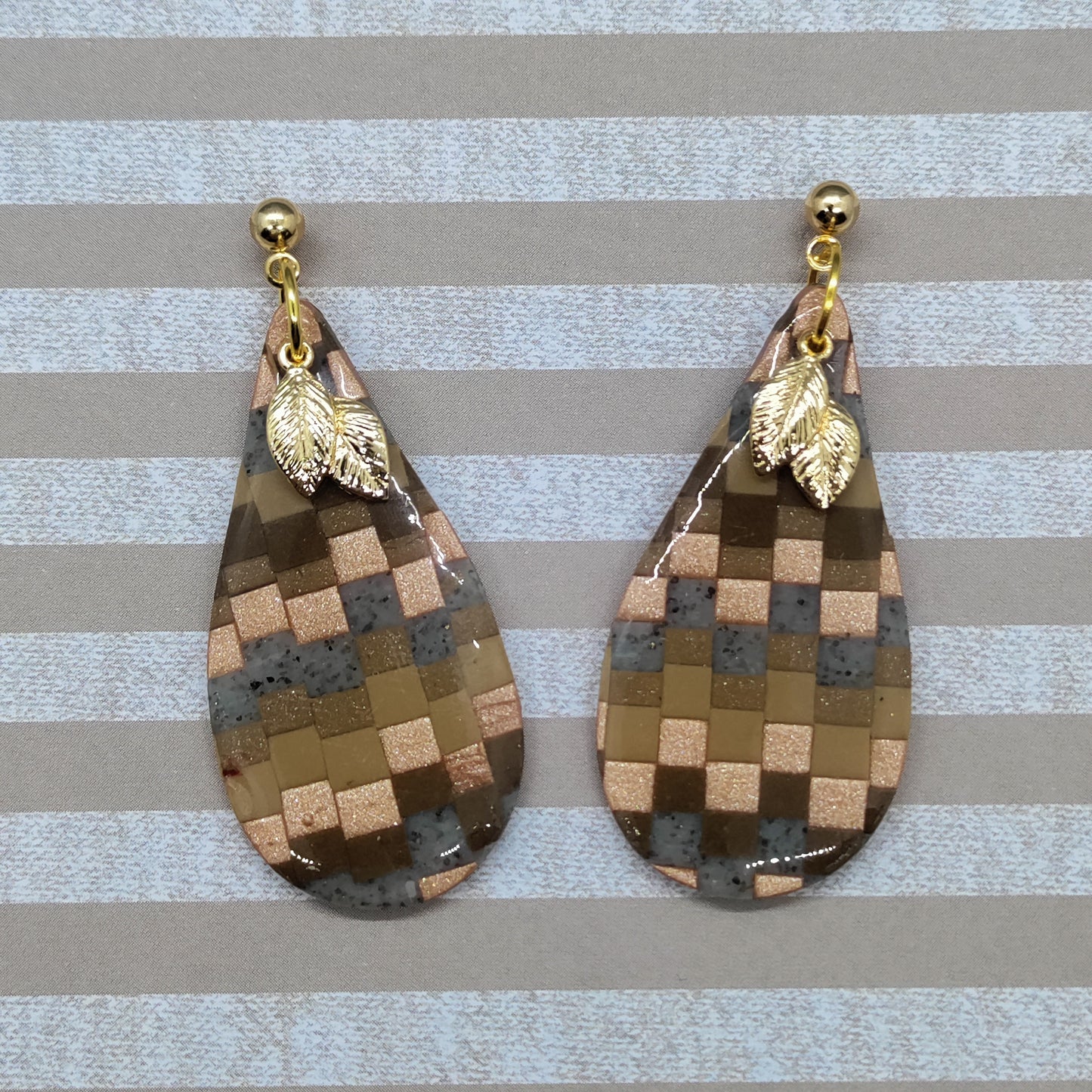 Teardrop-shaped earrings with checkered pattern and gold leaf accents