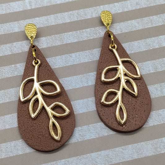 Brown teardrop earrings with gold leaf designs on a striped background