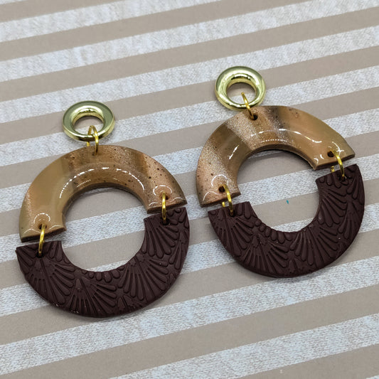 Pair of brown and beige earrings on a striped background