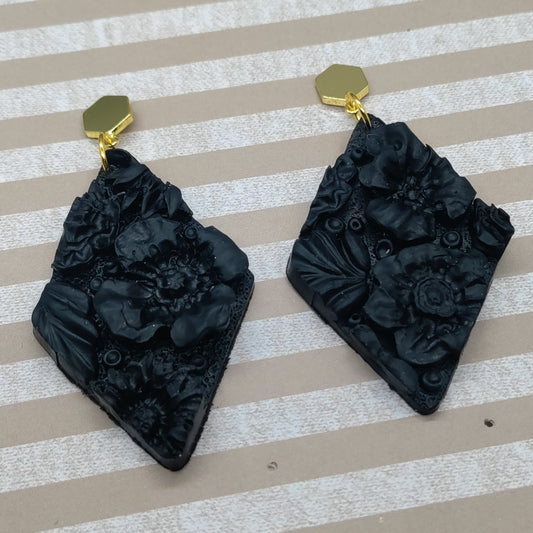 Black floral earrings on a striped background