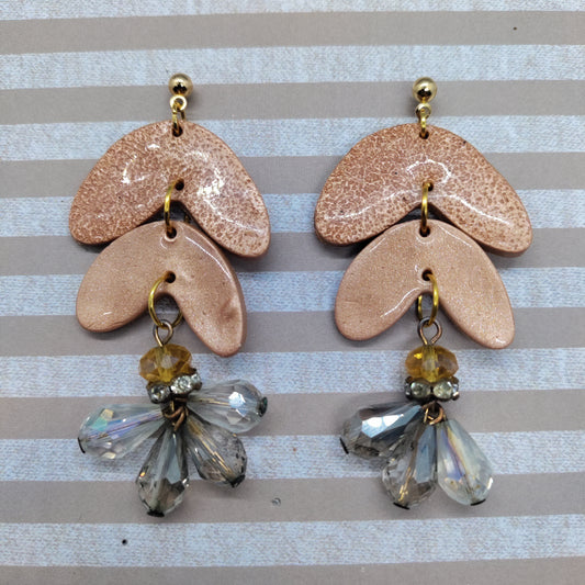 Pair of ceramic earrings with beaded drops on a striped background