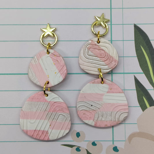 Pair of pink and gold earrings on a lined paper background