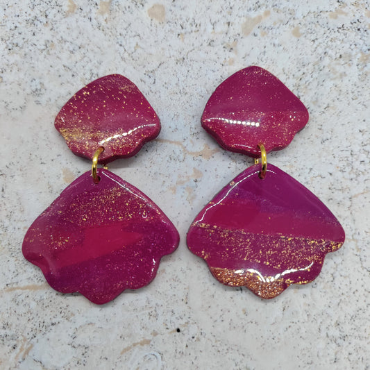 Pair of pink earrings with gold accents on a textured surface