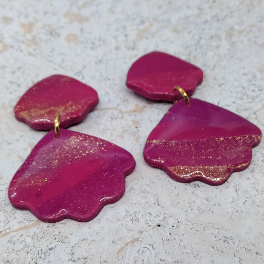 Pink earrings with gold accents on a textured surface