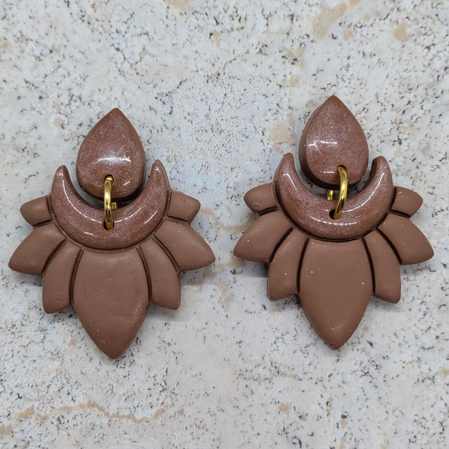 Pair of brown earrings on a light gray surface