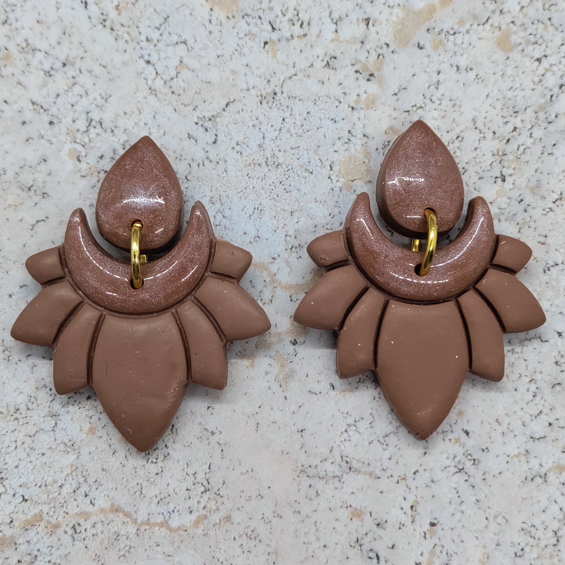 Pair of brown earrings on a light gray surface