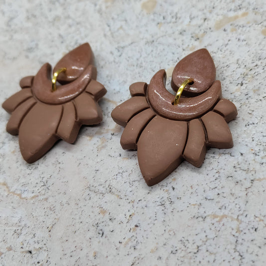 Pair of brown ceramic earrings on a speckled surface