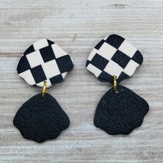 Pair of earrings with checkered top and black bottom. 