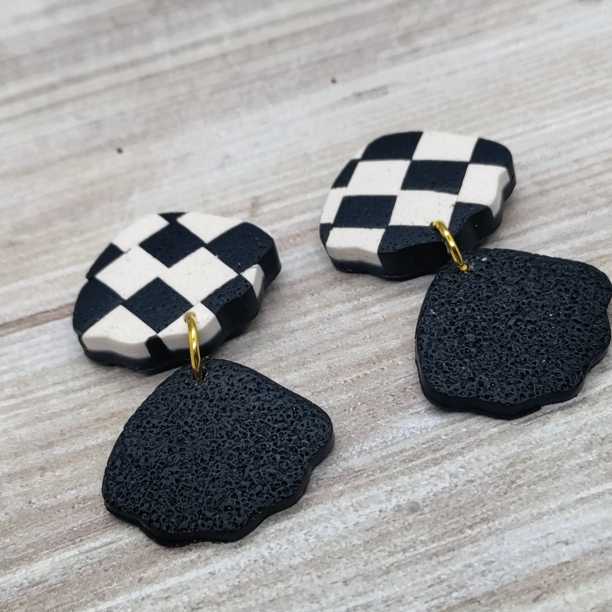 Pair of earrings with checkered top and black textured bottom.
