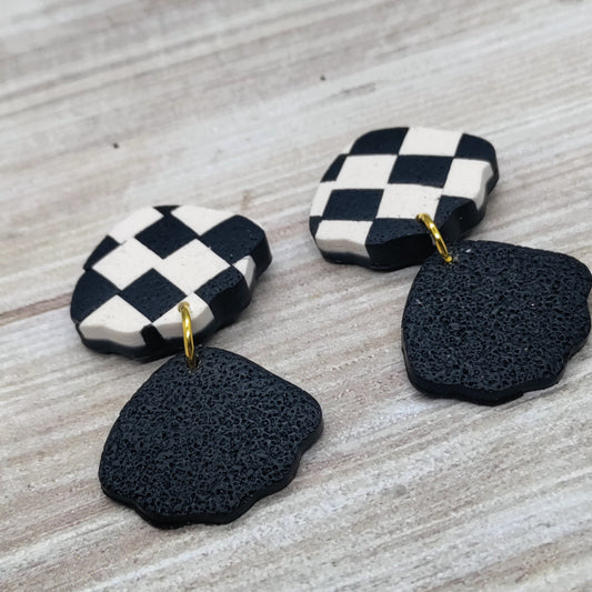Pair of earrings with checkered top and black textured bottom.