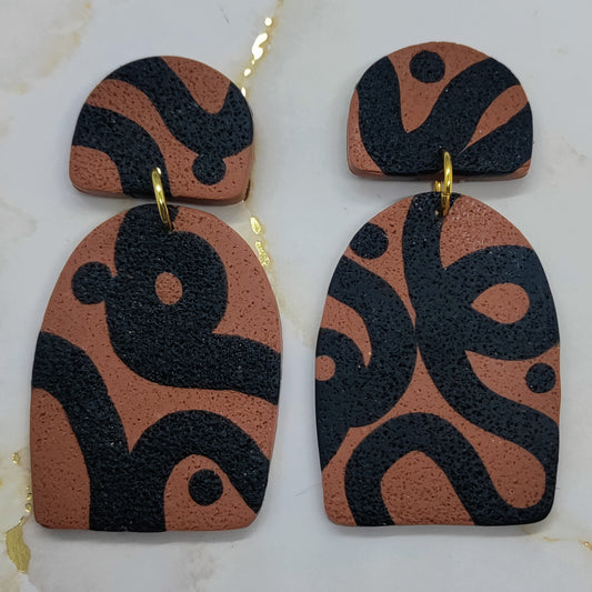 Pair of earrings with brown and black abstract design on a white background