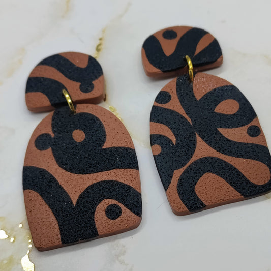 Pair of earrings with black and brown pattern on a white background