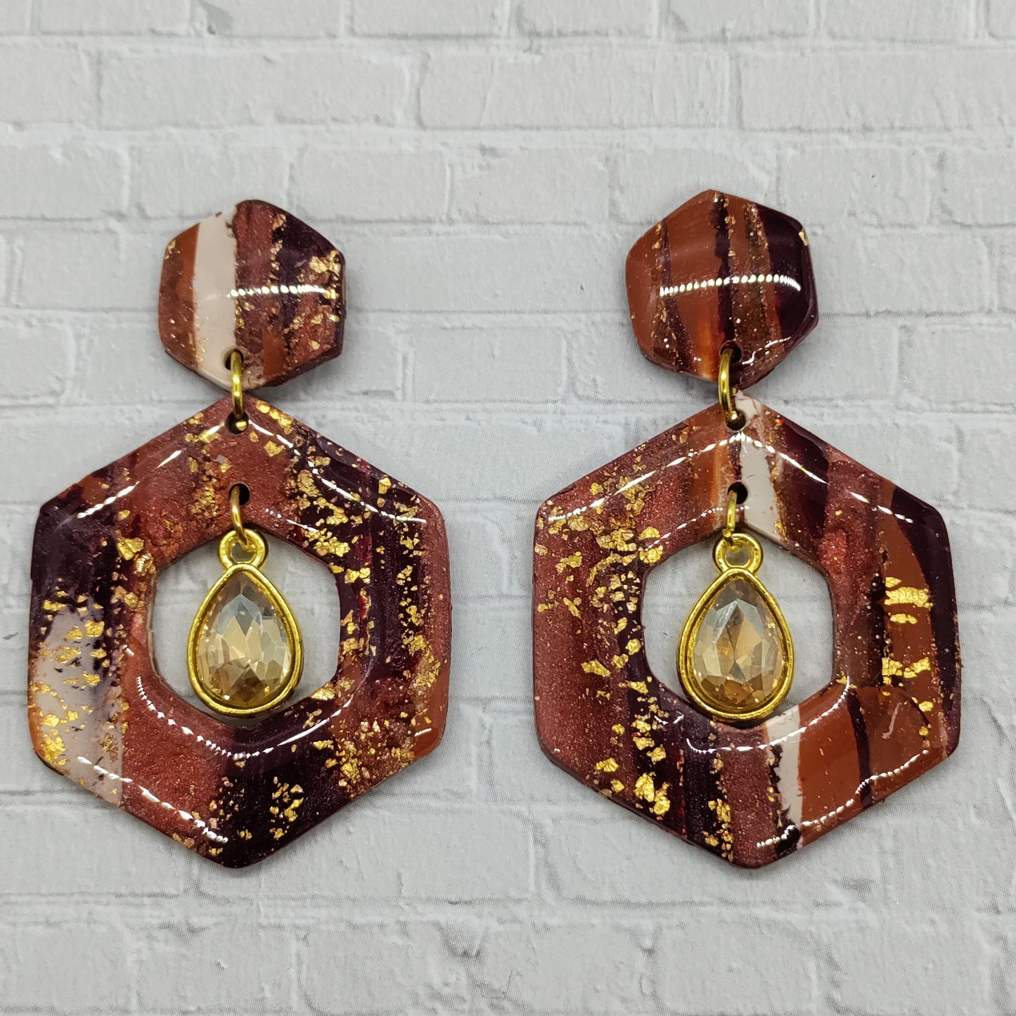 Hexagonal earrings with gold accents on a textured gray background
